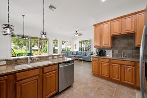 A kitchen with wooden cabinets, a dishwasher, and a built-in oven. - Game Room • Arcade Games • Private Pool • Guest House • 7521 (Kissimmee)