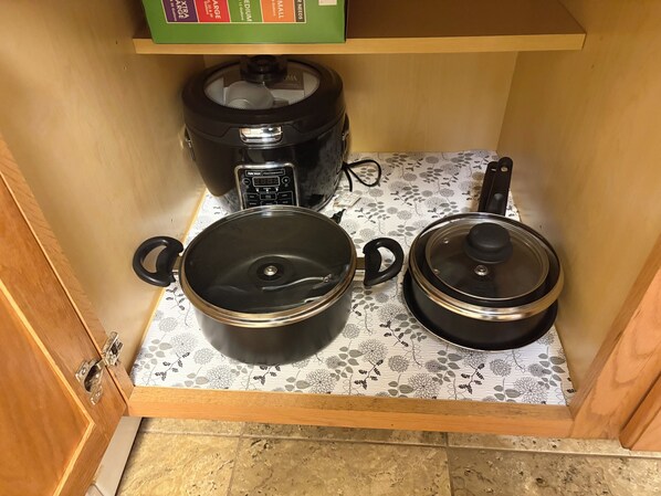 A kitchen with a stove, a rice cooker, and a pressure cooker on a patterned countertop.