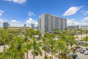 A high-rise hotel with a modern design, surrounded by palm trees and a parking area. - Hollywood Oasis Familiar |Playa | Piscina | Balcón (Hollywood)