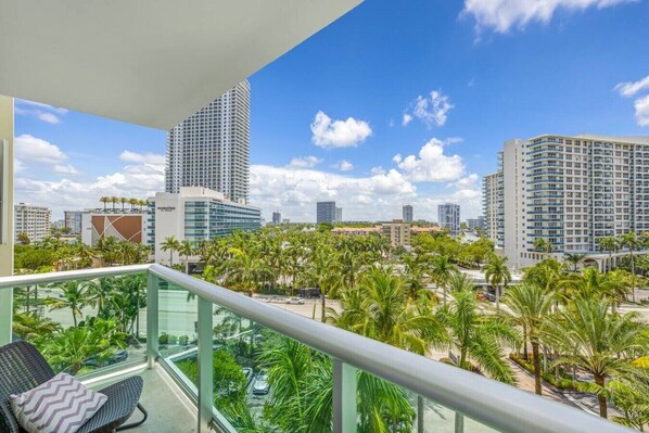 Ein Balkon mit Blick auf eine Skyline, Palmen und ein Gebäude im modernen Stil.