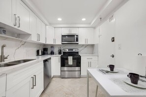 A modern kitchen with white cabinetry, stainless steel appliances, and a white countertop. - Hollywood Oasis Familiar |Playa | Piscina | Balcón (Hollywood)