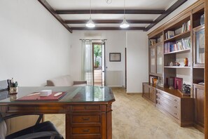 Une pièce comprenant un bureau, une bibliothèque, un radiateur et une porte donnant sur un espace extérieur.