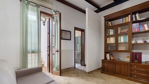 A living room with a sofa, a bookshelf, and a door leading to a hallway. - Holiday Home "Dimora Collina 1" with Wi-Fi and Air Conditioning (Sannicola)