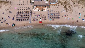 An aerial view of a beach resort with multiple sun loungers, a central building, and clear turquoise waters. - Holiday Home "Dimora Collina 1" with Wi-Fi and Air Conditioning (Sannicola)