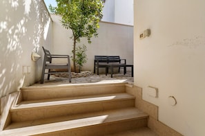 Un conjunto de escalones exteriores que conducen a una zona de estar con un árbol y un banco.