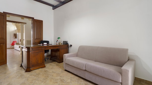 A room with a wooden desk, a beige sofa, a red chair, and a large mirror. - Holiday Home "Dimora Collina 1" with Wi-Fi and Air Conditioning (Sannicola)