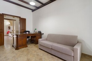 Ein Zimmer mit einem Holztisch, einem beigen Sofa, einem roten Sessel und einem großen Spiegel.