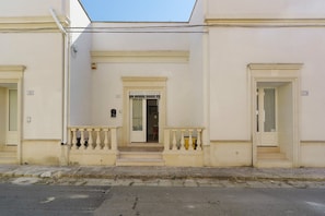 Un edificio con una facciata simmetrica, numeri sulle porte e un ingresso centrale con un piccolo portico.