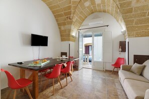 A dining area with a long table, red chairs, a flat-screen TV, and a stone wall. - Holiday Home "Dimora Collina 1" with Wi-Fi and Air Conditioning (Sannicola)