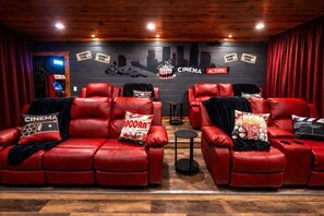 A cinema-themed room with red leather sofas, popcorn-themed pillows, and a wall with cinema-related decorations. - Brand New Design! Huge Pool Cabin@ Blackhawk Lodge (Sevierville)