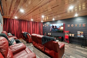 A cinema room with red leather seating, a large screen, and a popcorn stand. - Brand New Design! Huge Pool Cabin@ Blackhawk Lodge (Sevierville)