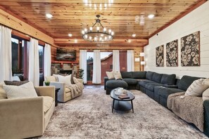 A cozy living room with a fireplace, wooden ceiling, and a large chandelier. - Brand New Design! Huge Pool Cabin@ Blackhawk Lodge (Sevierville)