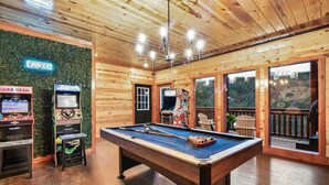Una mesa de billar en una habitación con paredes de madera y un adorno mural verde.