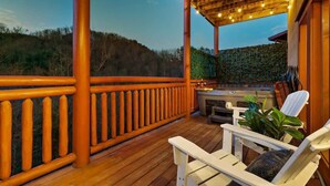 Una terraza de madera con zona de barbacoa, mobiliario exterior y vistas del paisaje circundante.