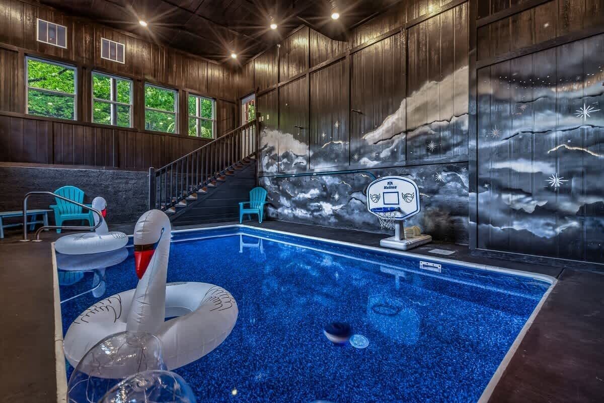 Ein Hallenbad mit Wandgemälde von Wolken und Sternen, einem Basketballkorb und einer Treppe, die zu einer oberen Ebene führt.