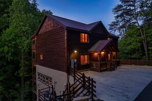 Eine zweistöckige Blockhütte mit Veranda und einer Treppe, die zum oberen Stockwerk führt.
