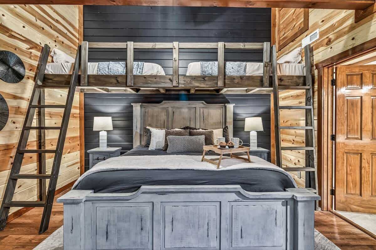 A bunk bed with a wooden headboard, a bedside table with a lamp, and a small table with a tray.