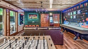 A room with a foosball table, a sofa, and a foosball table with a game on display. - Brand New Design! Huge Pool Cabin @ BIG STAR LODGE (Sevierville)