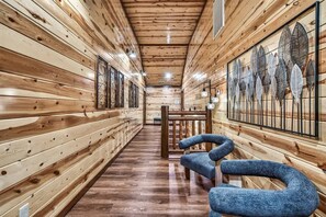 Un couloir intérieur en bois, avec des bancs et une œuvre d’art accrochée au mur.