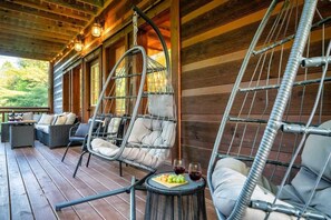 Eine Holzterrasse mit Korbstühlen und einem Tisch, der mit Früchten und Weingläsern bestückt ist.