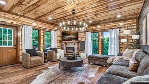 A cozy living room with a fireplace, wooden ceiling, and large windows. - Brand New Design! Huge Pool Cabin @ BIG STAR LODGE (Sevierville)