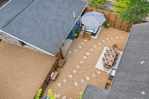 An outdoor patio with a table and chairs, a hot tub, and a wooden deck. - Private Mini Golf Course, Main House + Clubhouse, HotTub, Games, Walk to Bars (Nashville)