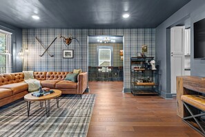 Ein modernes Wohnzimmer mit einem Ledersofa, einem Couchtisch und einem karierten Teppich.