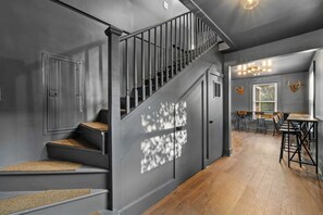 Eine Treppe mit dunkler Wand und Holzhäusern, die zu einem Essbereich mit Tisch und Stühlen führt.
