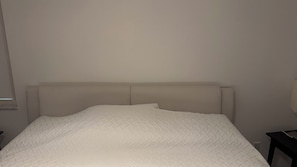 Ein Bett mit Kopfstütze und einer weißen Decke.