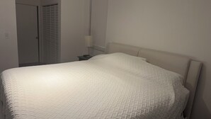 Una camera da letto con un letto, un comodino, una lampada e una porta.