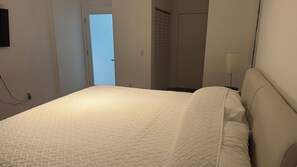 A bedroom with a bed, a bedside lamp, and a door leading to a bathroom. - Charming 2-bedroom apartment with AC in beautiful Aventura (Aventura)