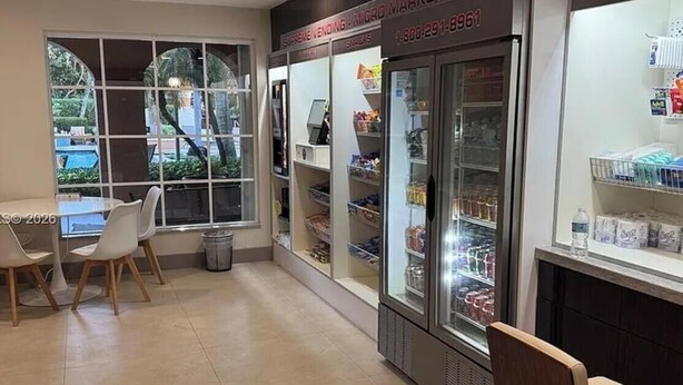 Un negozio pulito e ben illuminato, con vetrine refrigerate, un cestino e un'area salotto con sedie.