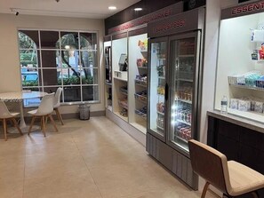 Una tienda limpia y bien iluminada con vitrinas refrigeradas, un basurero y un área de descanso con sillas.