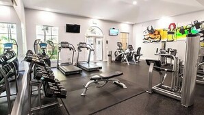 Una palestra con diverse attrezzature per l'allenamento, tra cui tapis roulant, manubri e macchinari per pesi.