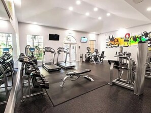 Ein Fitnessstudio mit verschiedenen Trainingsgeräten, darunter Laufbänder, Kurzhanteln und Kraftgeräte.