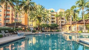 Una piscina circondata da palme e un edificio a più piani con balconi.