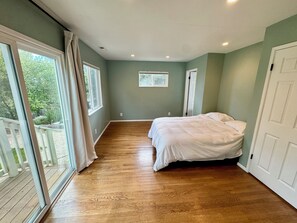 Un dormitorio con una ventana grande, una cama y una puerta.