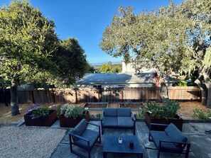 An outdoor patio with a wooden fence, a covered barbecue area, and a seating arrangement. - Monterey Getaway - Fabulous 3-bedroom house in Monterey (Monterey)