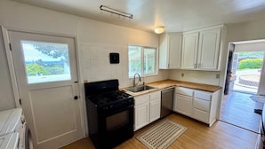 A compact kitchen with a stove, sink, and white cabinets. - Monterey Getaway - Fabulous 3-bedroom house in Monterey (Monterey)