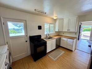 A compact kitchen with a stove, sink, and white cabinets. - Monterey Getaway - Fabulous 3-bedroom house in Monterey (Monterey)