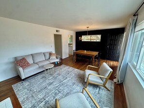Een moderne woonkamer met een bank, salontafel, eettafel en stoelen.