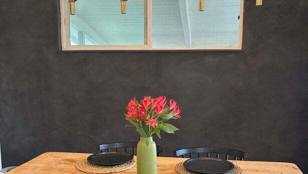 A dining table with black plates, a green vase with red flowers, and a modern chandelier. - Monterey Getaway - Fabulous 3-bedroom house in Monterey (Monterey)
