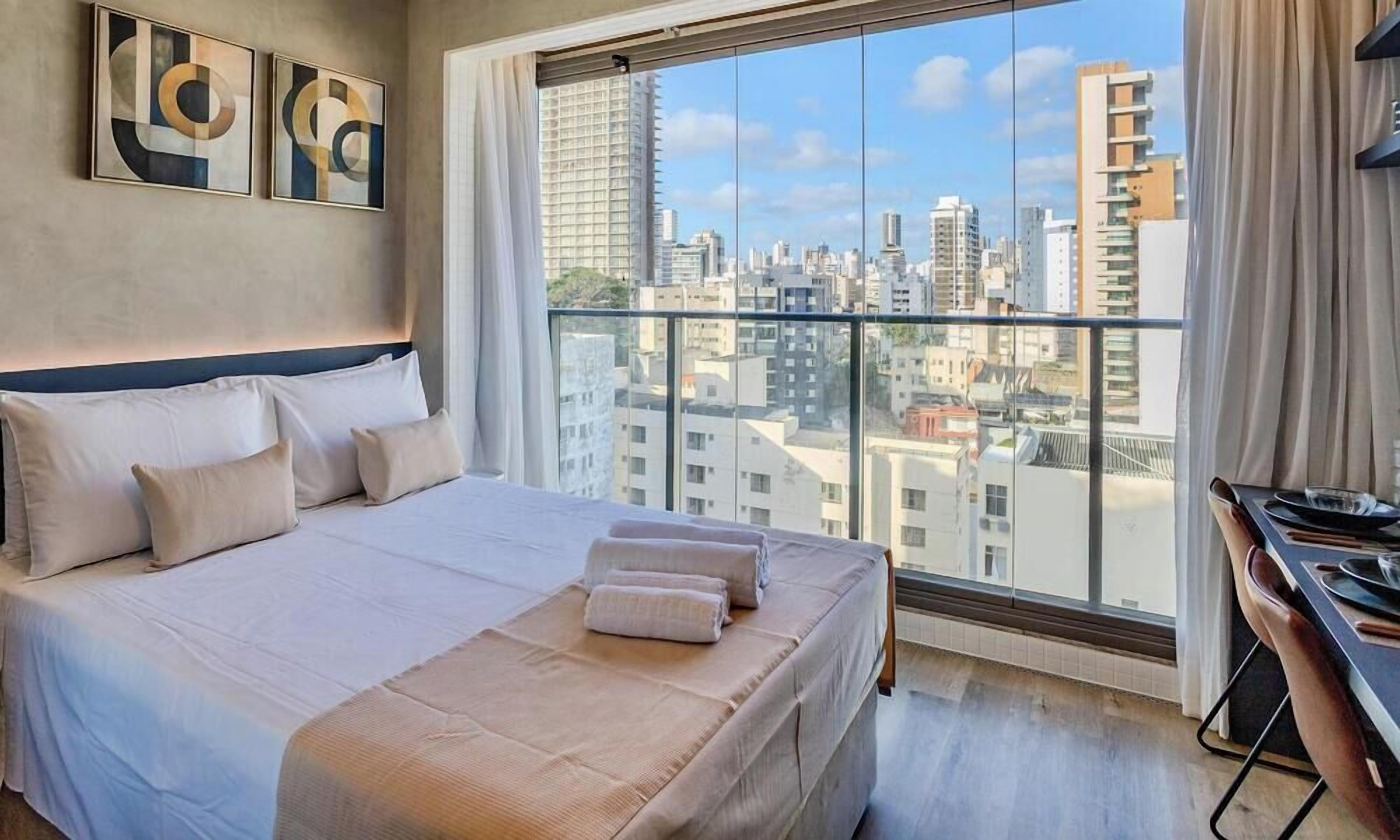 A hotel room with a large bed, a desk, and a city view.