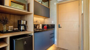 Una cucina compatta con frigorifero integrato, macchina del caffè e lavello.