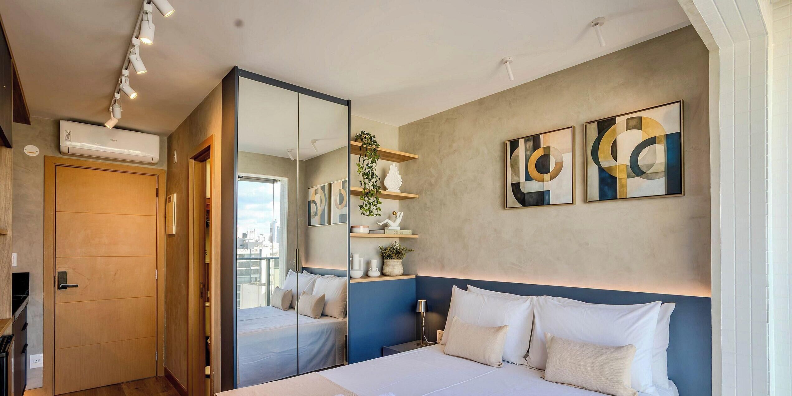 Ein modernes Schlafzimmer mit einem großen Bett, einem Kleiderschrank, einem Spiegel und Bildern an der Wand.