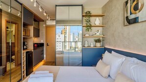 Una camera moderna con un letto grande, un armadio e vista sulla città attraverso una porta di vetro.