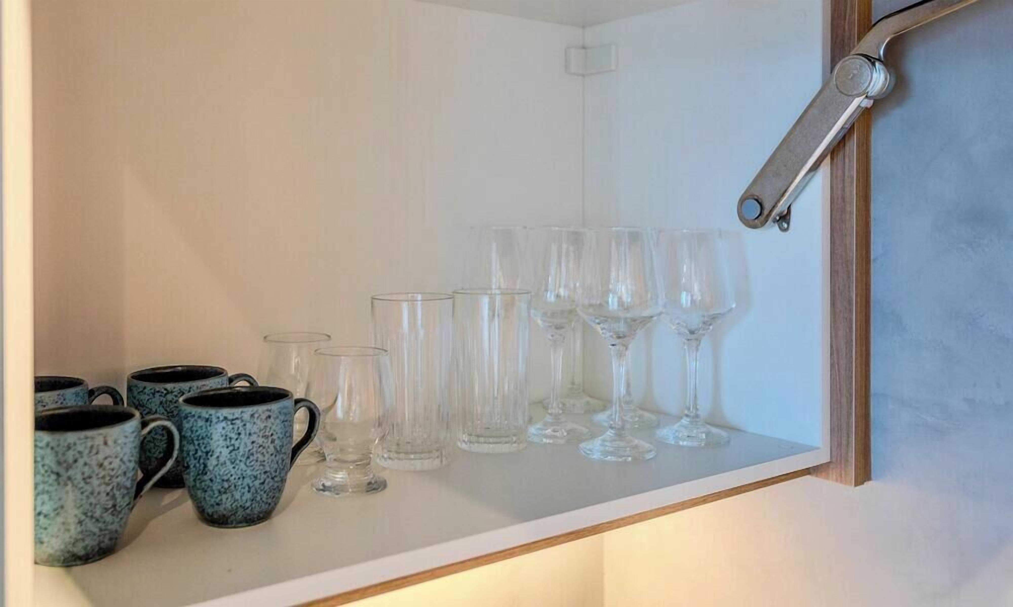 Une étagère avec de la verrerie transparente et des tasses à motifs bleus.