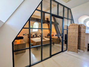 A bedroom with a sloped ceiling, a bed, a nightstand, a lamp, and a window.