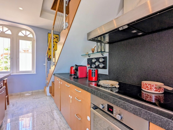 A modern kitchen with a built-in oven, a coffee maker, and a red toaster.