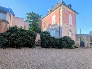 A building with a red facade, a stone base, and a gravel driveway. - Villa Teranga - Terre d'Accueil - Château Colin (Belleau)